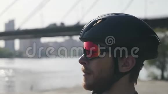 年轻的白种人留着大胡子的骑自行车的人看起来很直骑自行车的人戴着黑色头盔和太阳镜的肖像视频的预览图