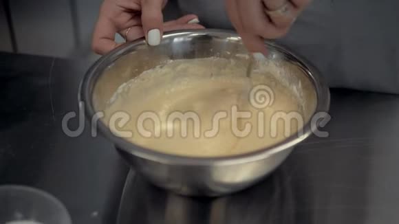 用搅拌器揉面女性的手把面团混合在铁板上视频的预览图