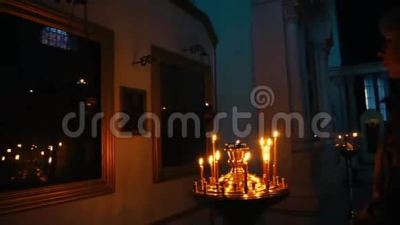 年轻的基督教妇女在东正教教堂前祈祷的图标与蜡烛的背景慢动作视频的预览图
