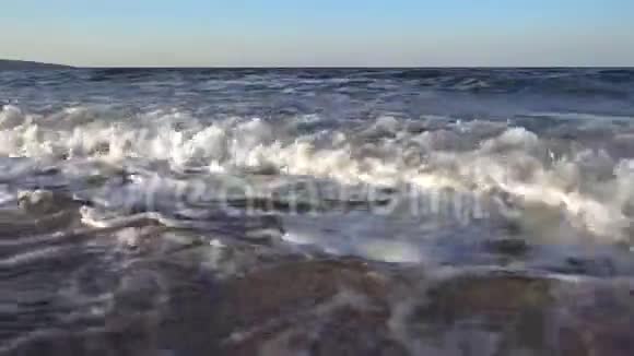 夏季傍晚日落时大海的巨浪冲刷着沙滩上的贝壳视频的预览图