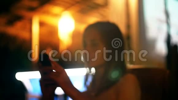 快乐迷人的年轻女商人微笑使用智能手机购物应用程序在大气之夜户外酒廊酒吧咖啡馆视频的预览图
