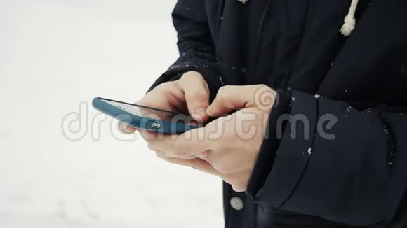 在降雪的情况下用智能手机男人的双手合上视频的预览图