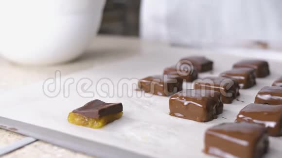 贝克手把糖果浸在融化的巧克力里放在烤盘上巧克力糖果的生产视频的预览图