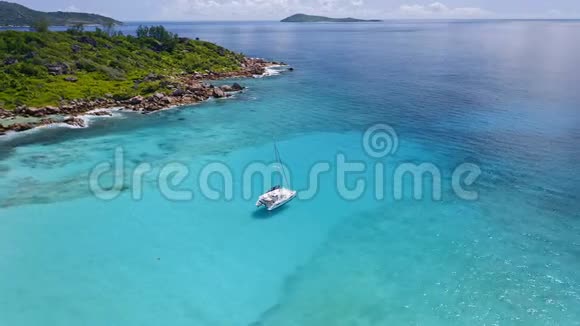 空中4k无人驾驶飞机的镜头孤独的白色游艇停泊在水晶般清澈的绿松石泻湖水上的热带拉迪盖岛视频的预览图