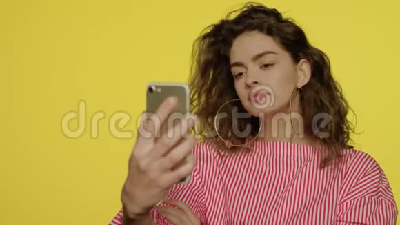 黄底手机自拍照片的年轻女子视频的预览图