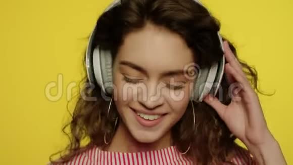 年轻女子用耳机听音乐黄色耳机上的快乐女孩视频的预览图