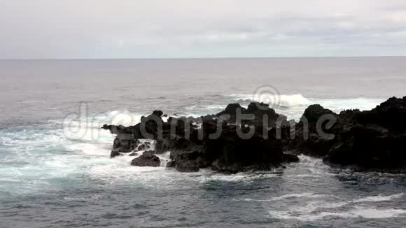 波浪在涨潮时与岩石海岸交叠视频的预览图