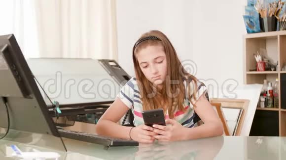 无聊的少女坐在办公桌前在智能手机上上网视频的预览图