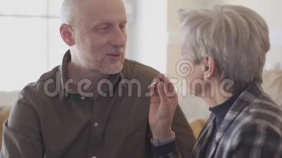 老两口坐在沙发上一个头发灰白的女人把巧克力糖放在秃头男人的嘴里视频的预览图