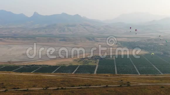 几架滑翔伞正在日落谷上空飞行夏季空中无人驾驶飞机上的葡萄园和山脉就在地平线上视频的预览图