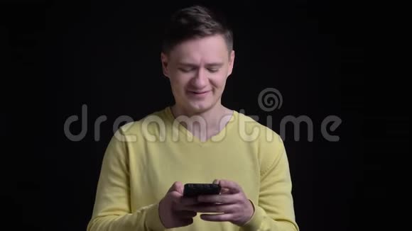 穿着黄色毛衣的中年白种人微笑着看着智能手机赞许地点头视频的预览图