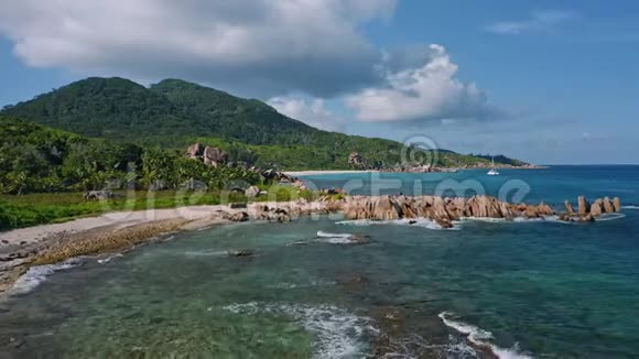 空中无人机拍摄的热带海岸线花岗岩岩石和海浪滚动海岸孤独的双体船视频的预览图