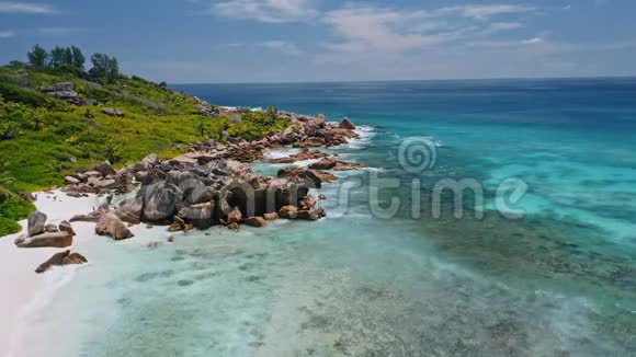 空中飞行镜头沿着热带海岸线与巨大的花岗岩岩石和蓝色海浪在天堂海滩安塞可可La视频的预览图