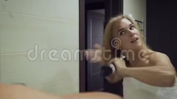 漂亮的女人在浴室洗澡后用刷子烘干机烘干头发视频的预览图