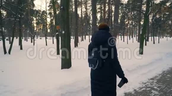 红发女孩走在白雪皑皑的公园里视频的预览图