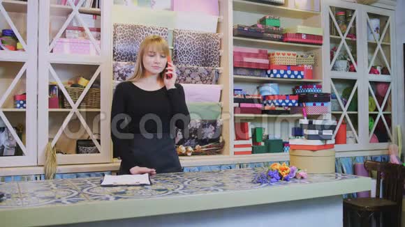 花店的年轻女职员通过电话和笔记本聊天视频的预览图