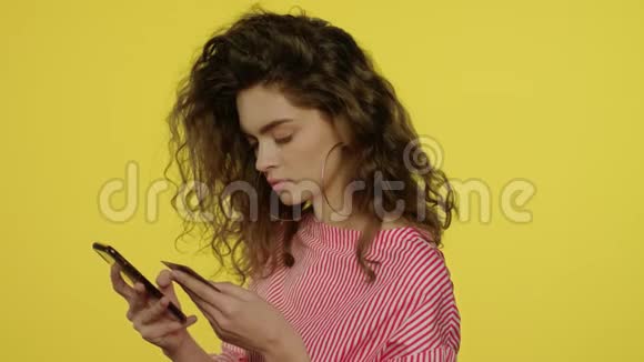 黄色工作室中使用智能手机支付银行卡的年轻女性视频的预览图