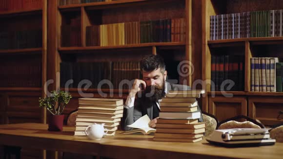 严肃的男学生在图书馆看书有胡子的人在书架背景上看书经典男人视频的预览图