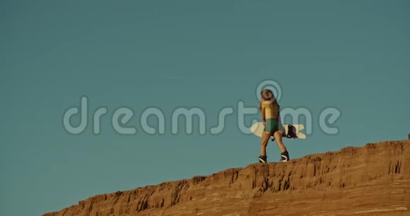 高高的悬崖上的女性沙艇运动员夕阳的光芒视频的预览图