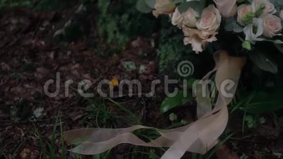 非常美丽的新娘花束躺在草地上的一棵树附近视频的预览图