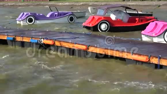 塑料彩色船只形状的汽车在海水波浪和木制码头视频的预览图