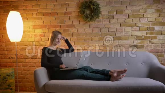 年轻漂亮的女千禧一代坐在笔记本电脑上看电影开心地笑着的肖像视频的预览图