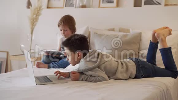 父母的男孩早上笔记本电脑和平板电脑睡觉兄弟玩电脑游戏兄弟姐妹和小玩意视频的预览图
