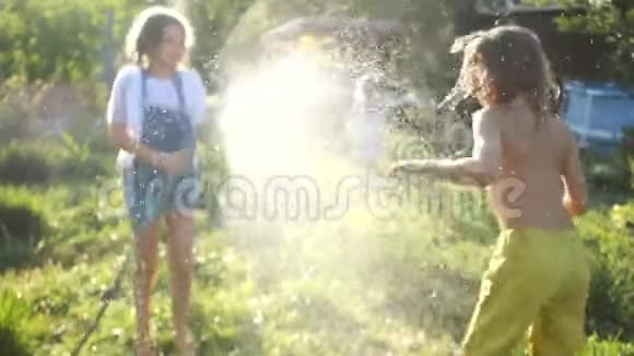 两个孩子在夏天的花园里玩洒水哥哥姐姐暑假热水游戏视频的预览图