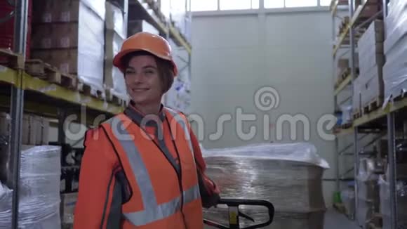一位辛勤工作的妇女穿着制服的工人在仓库的一排排货架之间用箱子拉动手推车视频的预览图