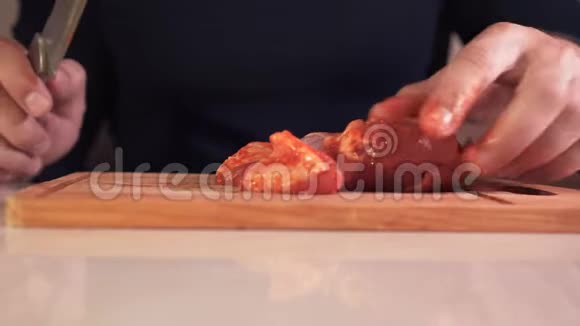 一个男人的手在切割板上切生肉特写镜头视频的预览图
