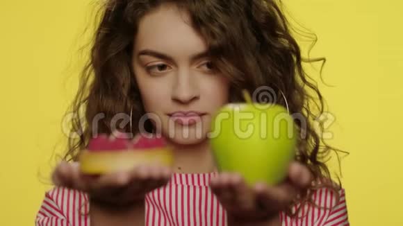 在黄色的工作室里年轻女子手里拿着苹果和蛋糕视频的预览图