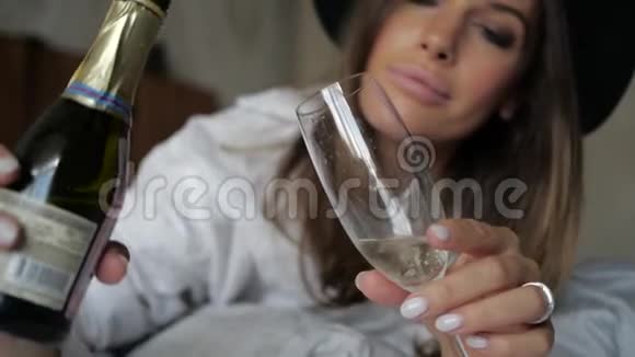 一个漂亮的女人把香槟倒进她的杯子里视频的预览图