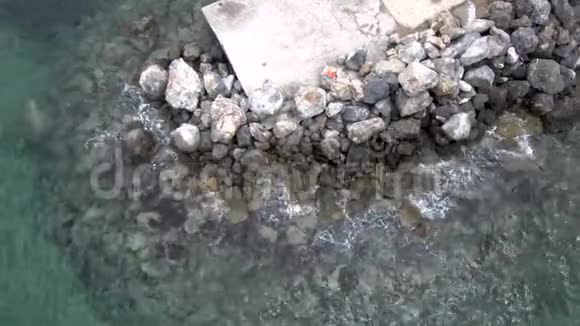 夏季鸟瞰绿松石海在Halkidiki地区有水在岩石上弹出向上和侧面移动视频的预览图