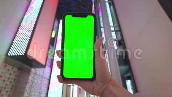 一只手握着一部智能手机手机背景是拉斯维加斯一家购物中心的霓虹灯视频的预览图