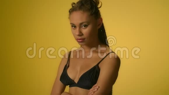 有非洲发型的女人在黄色背景下调情视频的预览图