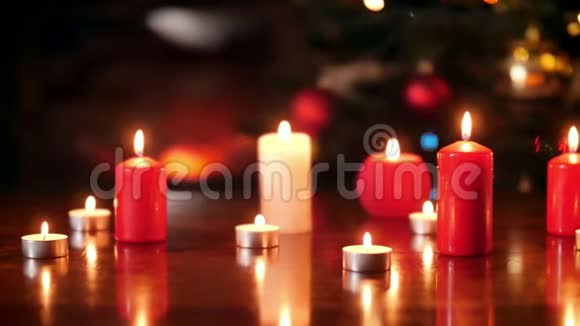 4k多利的视频在圣诞树上的木桌上点燃了许多红白蜡烛视频的预览图