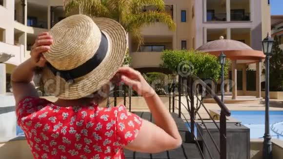 年轻快乐的女人邀请男人跟随她她的手穿着红色的裙子太阳镜和帽子在游泳池的桥上视频的预览图