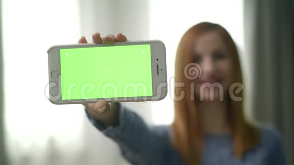 房间里漂亮的年轻女人用绿色屏幕显示设备视频的预览图
