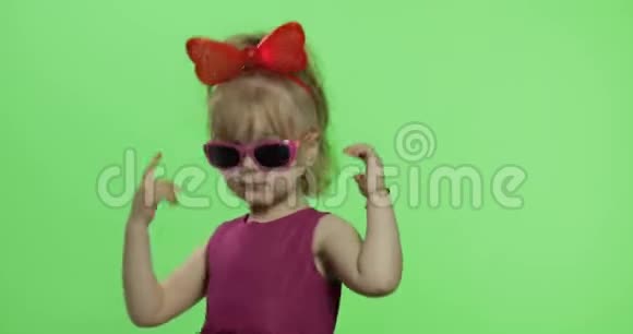 女孩穿着紫色连衣裙跳舞头上戴着太阳镜和红色丝带色度键视频的预览图