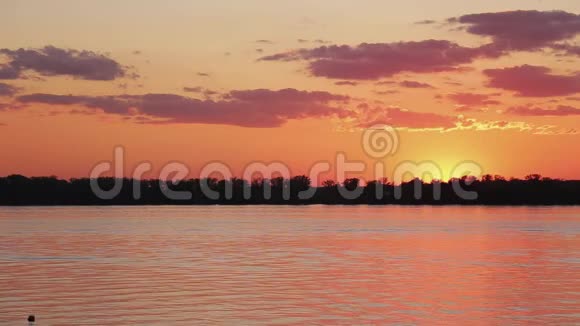 平静的河水和平静的水海岸线在美丽的橙色日落视频的预览图
