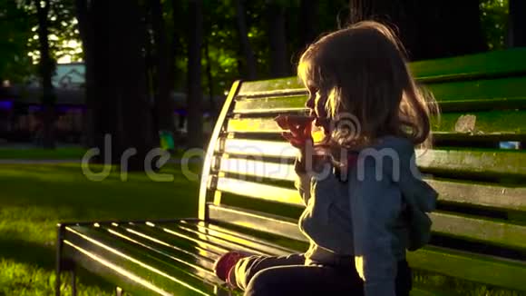 女孩在长凳上吃糖果视频的预览图