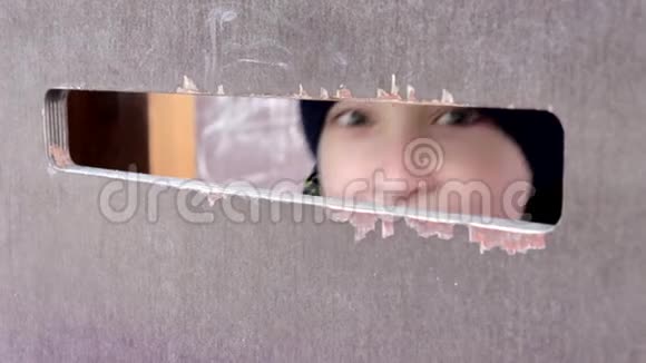 一个十几岁的男孩漂亮的眼睛透过木墙上的一个大洞窥视人类情感面部表情视频的预览图