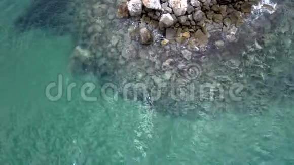 夏季鸟瞰绿松石海在Halkidiki地区有水在岩石上弹出向上和侧面移动视频的预览图