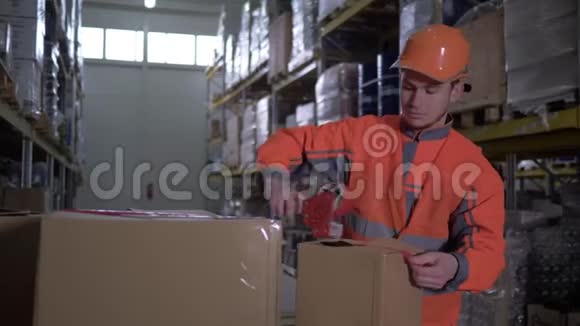 穿制服的工人在仓库用胶带装纸板箱视频的预览图