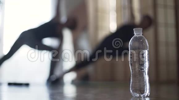 两个注意力不集中的女孩在室内做运动前景中的一瓶水健康生活方式娱乐视频的预览图