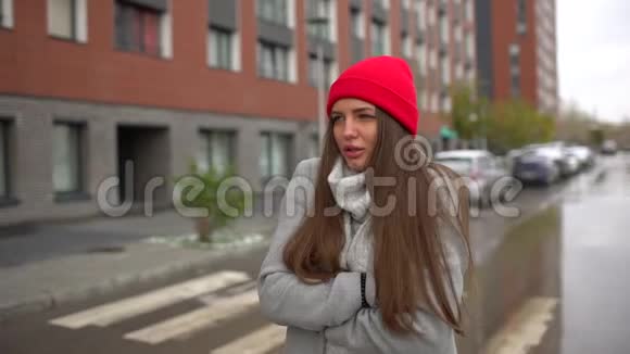 一位年轻悲伤的美丽女子的肖像一位在雨天寒冷的天气里在户外的城市街道上散步的女孩秋天视频的预览图