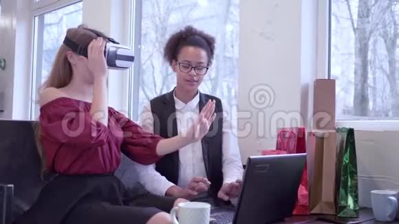 现代科技可爱的黑人女孩与电脑笔记本电脑和白种人女友进入虚拟现实眼镜游戏中视频的预览图