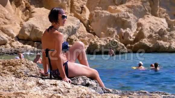 坐在红海边埃及落基海滩悬崖上的性感女孩视频的预览图