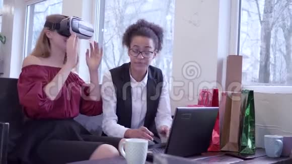 性格开朗皮肤黝黑的青春期少女带着电脑笔记本电脑白种人女朋友进入虚拟虚拟现实耳机游戏视频的预览图
