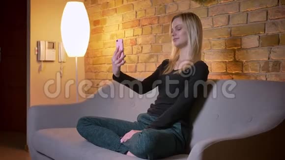 特写侧景照片年轻漂亮的女学生在电话上打视频坐着微笑视频的预览图